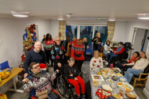 Staff and residents smiling at the camera at their Christmas party.